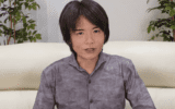 Masahiro Sakurai op een witte bank tijdens een video van zijn YouTube-kanaal